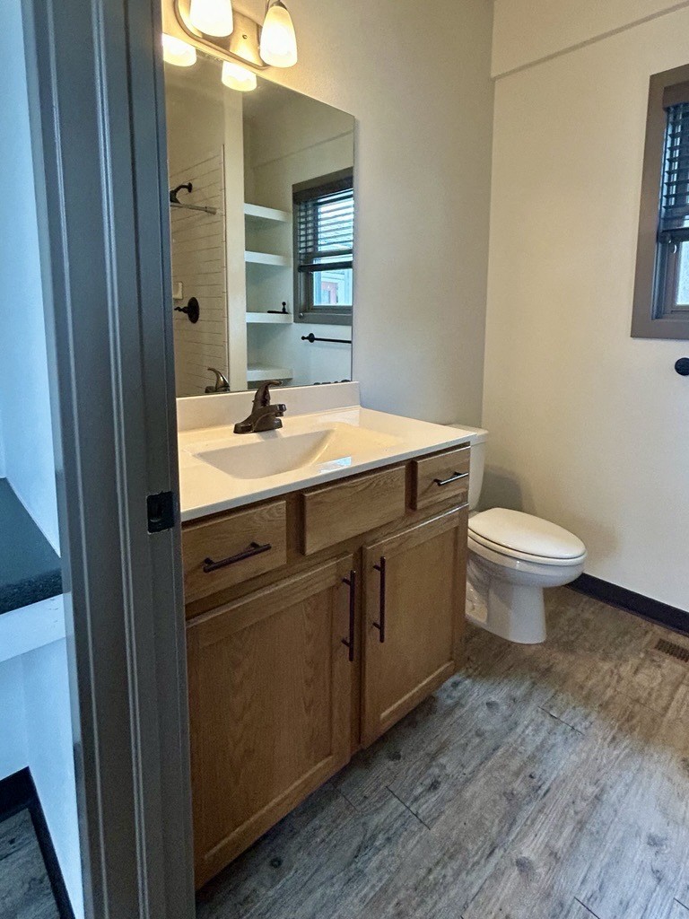 A bathroom with a toilet, sink, and mirror.